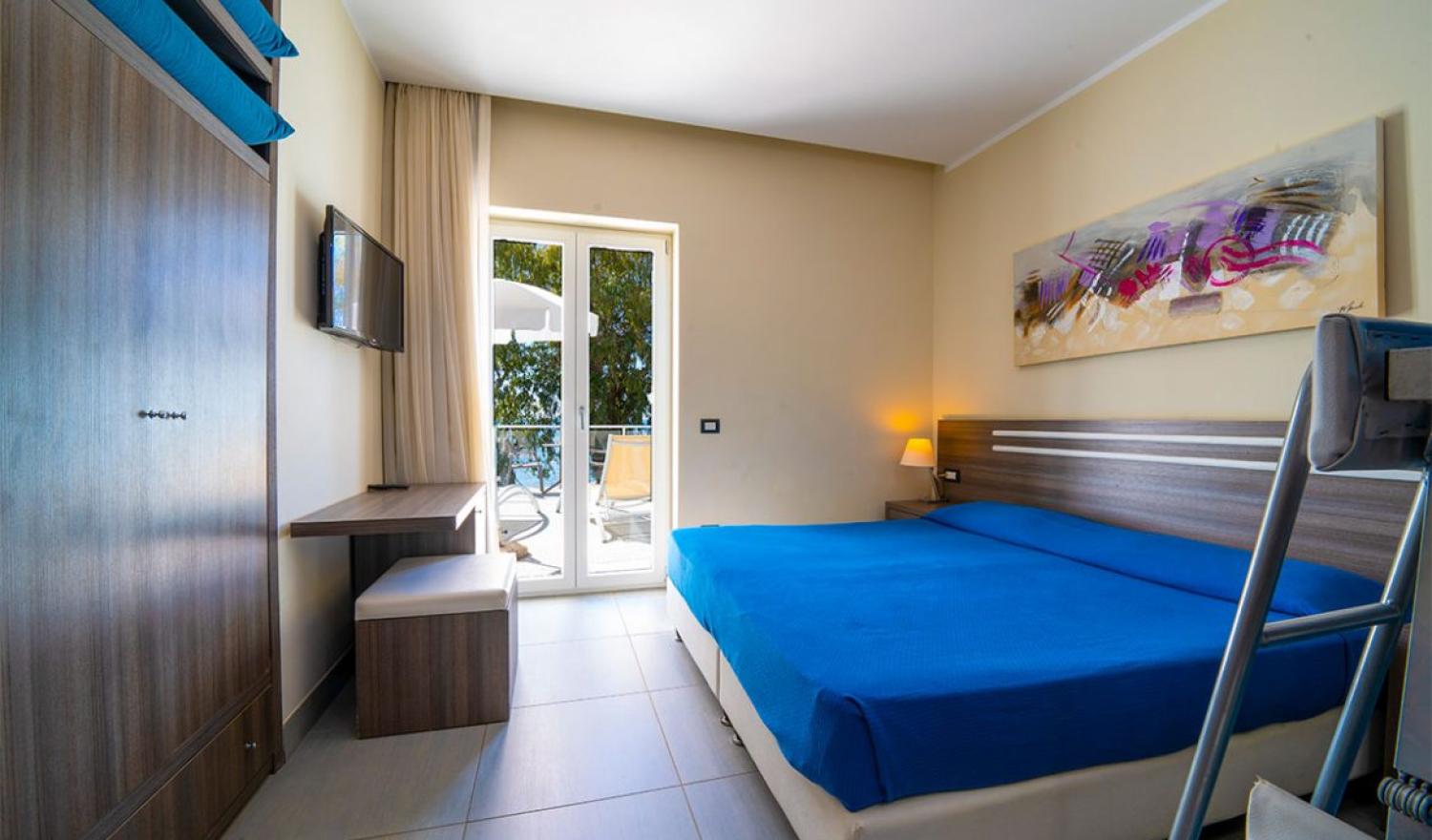 Camera moderna con letto matrimoniale, balcone, TV e decorazioni astratte.