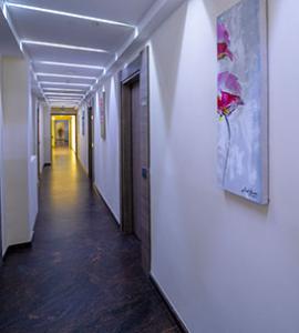Corridoio moderno con illuminazione a LED e quadri floreali sulle pareti.