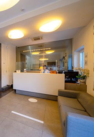 Reception moderna con divano grigio e illuminazione soffusa, ambiente accogliente e luminoso.