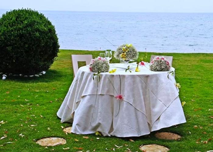 Tavolo all'aperto con fiori, vista mare, atmosfera romantica e rilassante.