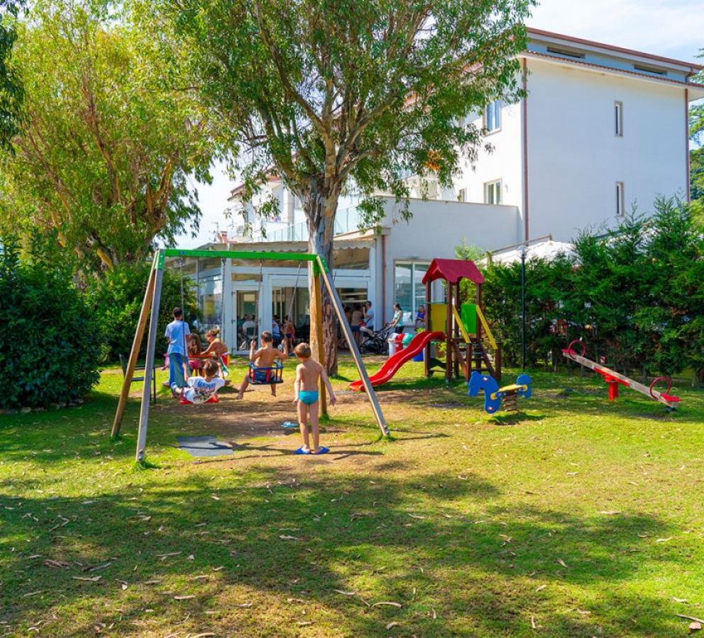 Parco giochi con bambini che giocano vicino a un edificio bianco.