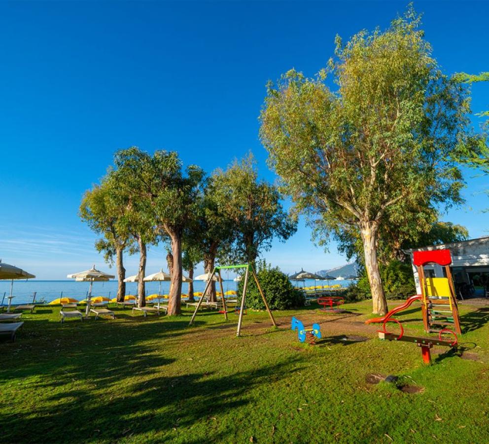 Spiaggia con lettini, ombrelloni e area giochi per bambini vicino al mare.