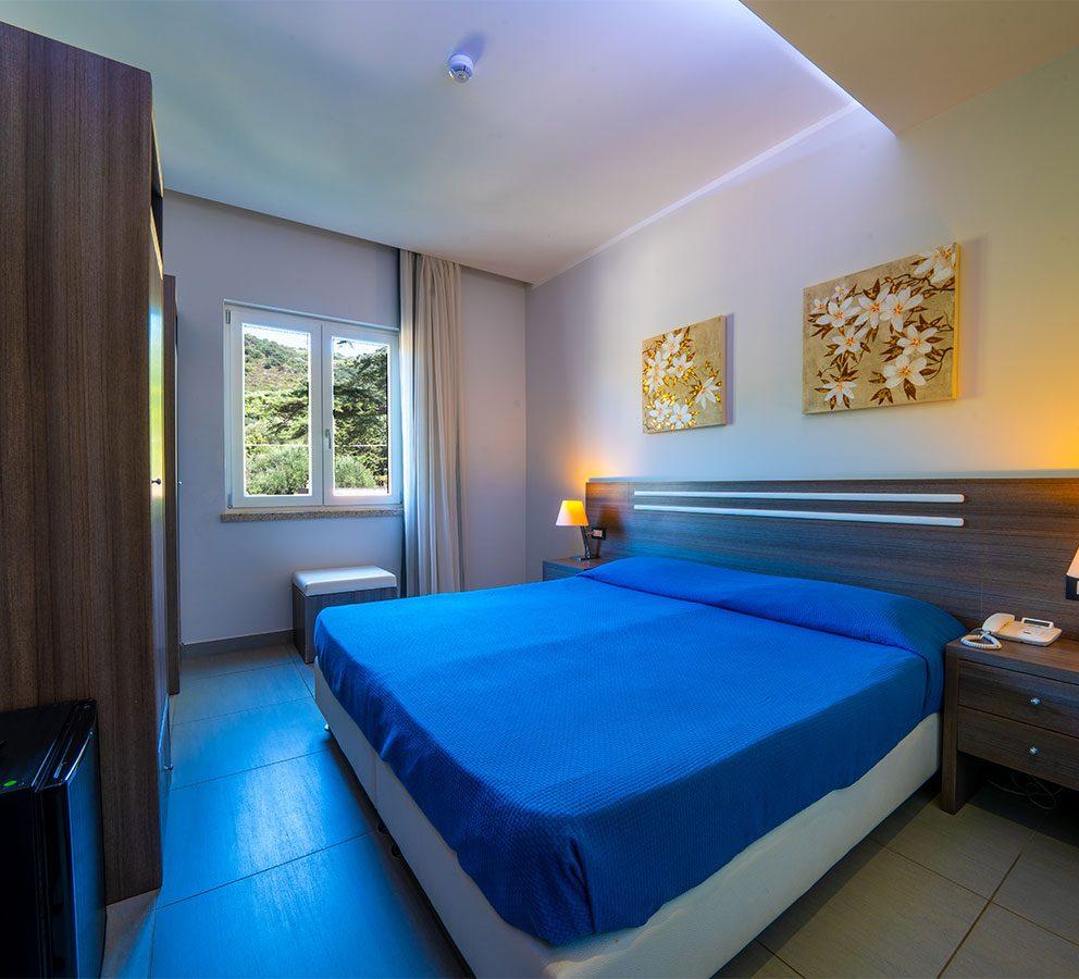 Camera moderna con letto matrimoniale, decorazioni floreali e vista sulla natura.