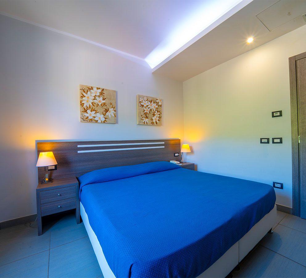 Camera da letto moderna con letto matrimoniale e illuminazione soffusa.