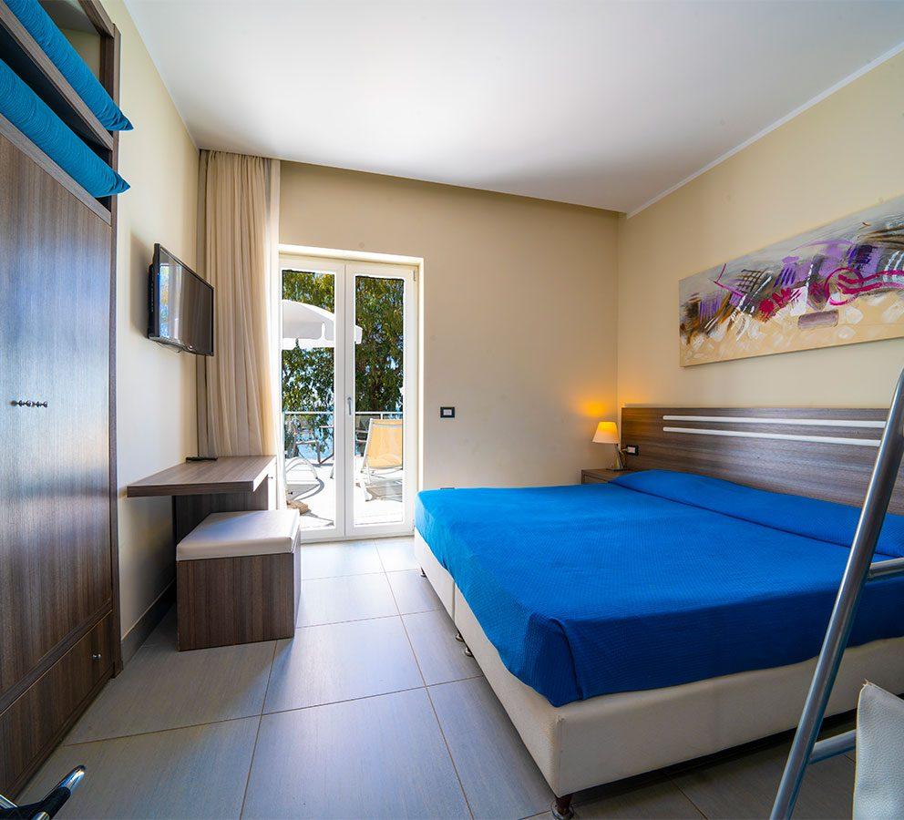 Camera moderna con letto matrimoniale, balcone, TV e decorazione astratta.